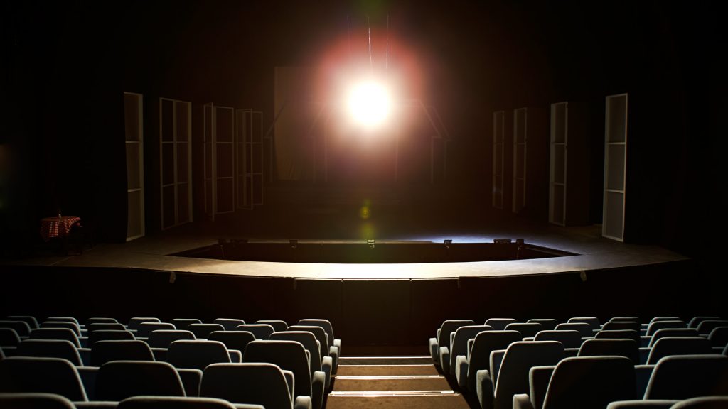 Tom scene og sal med et spotlight over scenen